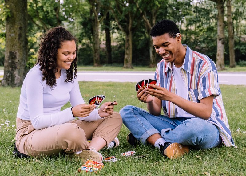 Man-and-woman-sitting-on-grass-playing-cards-2981571-e1575525052825.jpg